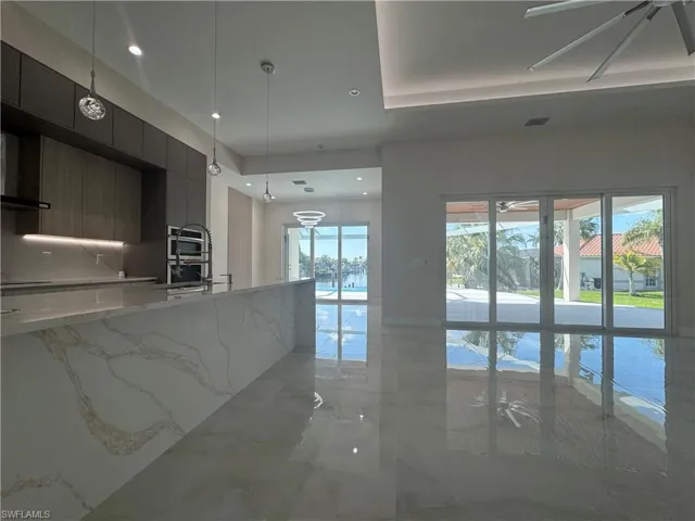 Kitchen featuring pendant lighting, ceiling fan, and light stone counters