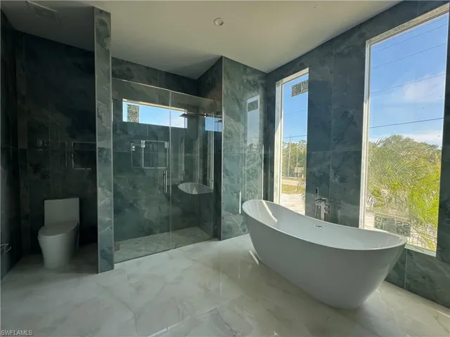 Bathroom with a healthy amount of sunlight, tile walls, and separate shower and tub