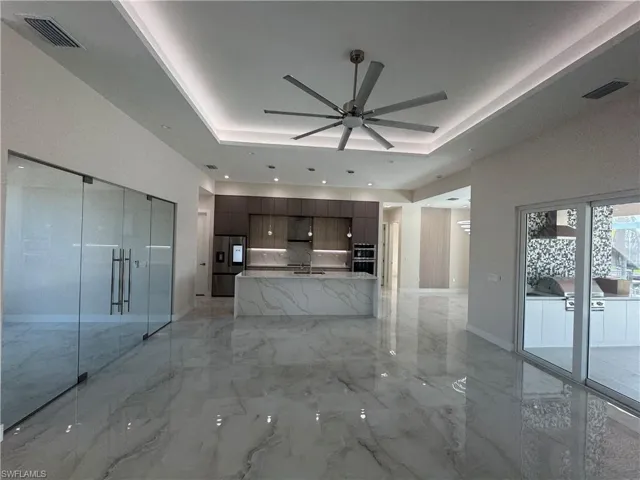 Unfurnished living room featuring a tray ceiling, ceiling fan, and sink