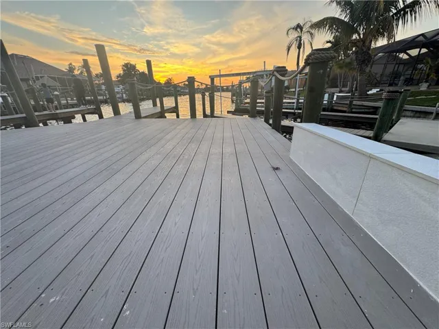 Deck at dusk featuring a boat dock and a water view