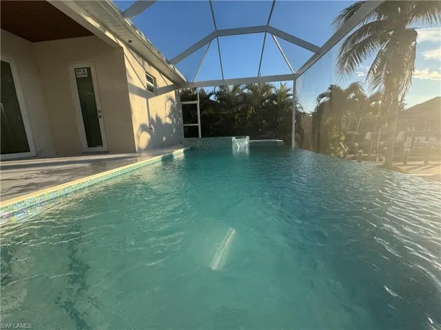 View of swimming pool with pool water feature, a patio, and a lanai