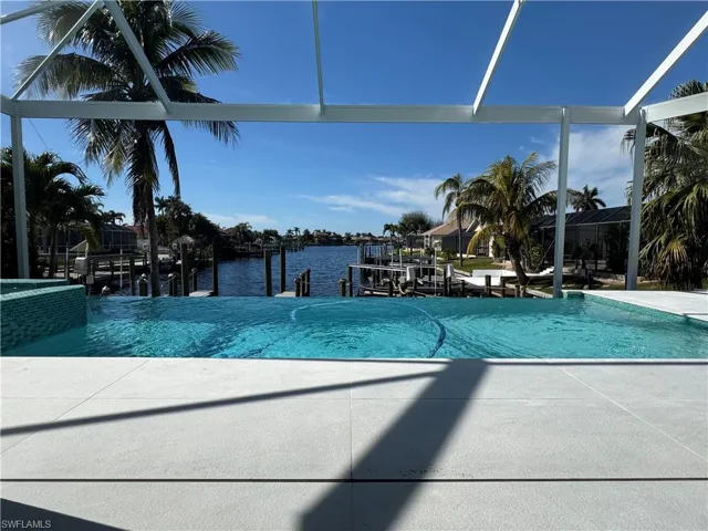 View of swimming pool with a dock, glass enclosure, and a water view