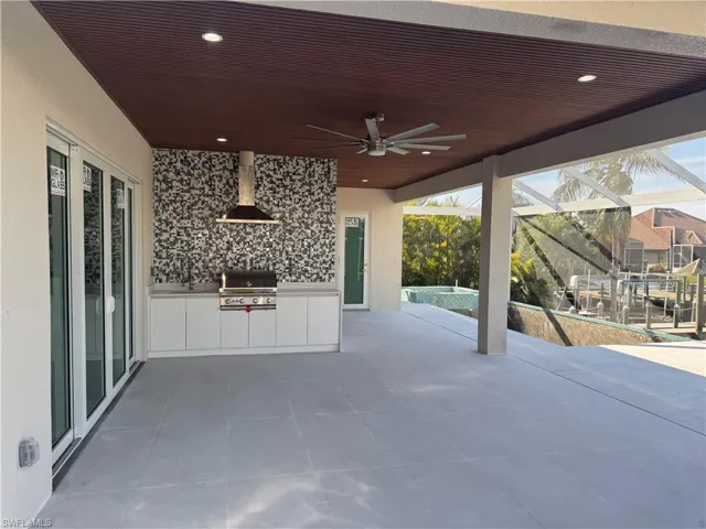 View of patio with grilling area, ceiling fan, a lanai, a pool, and exterior kitchen