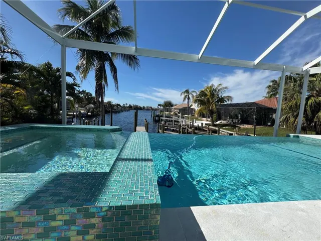 View of pool featuring a water view, a dock, and glass enclosure