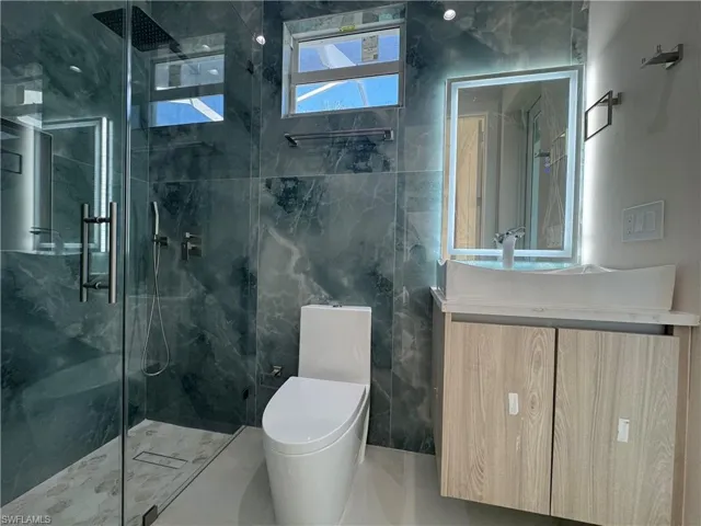 Bathroom with vanity, toilet, and a shower with shower door