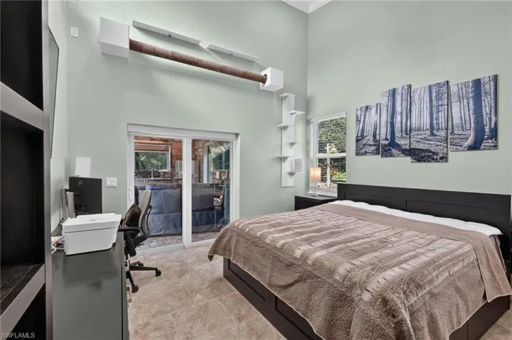 Vaulted ceilings with an exposed beam, tile flooring, built-in shelving, and direct patio access