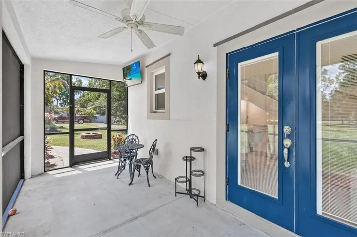 Screened outdoor patio featuring a ceiling fan, concrete flooring, and an exterior wall sconce
