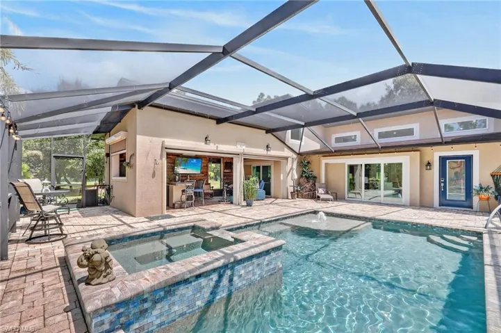 Screened lanai featuring a swimming pool, integrated spa, and brick paver decking