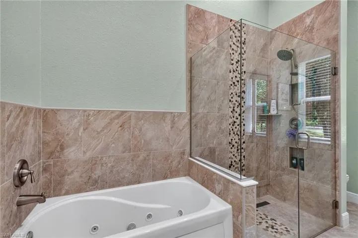 Tiled shower enclosure with frameless glass, a rain showerhead, and a mosaic tile accent