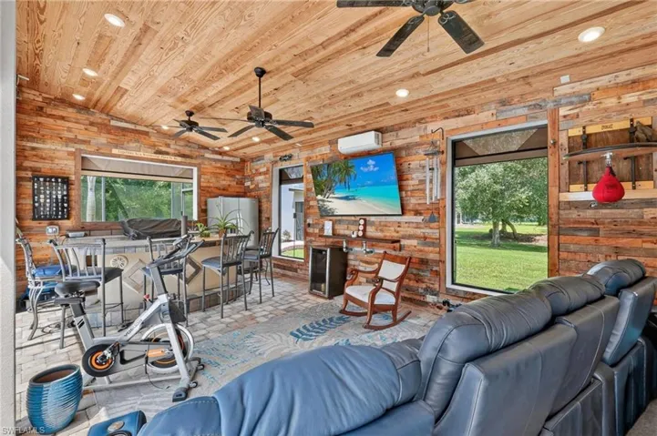 Wood plank walls and ceiling, recessed ceiling lighting, multiple ceiling fans, built-in bar, and rectangular windows