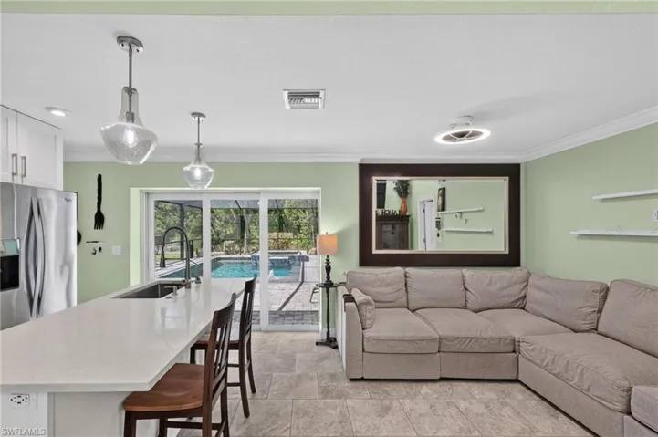 Kitchen island with light-toned countertop, dual pendant lighting, and stainless-steel appliances