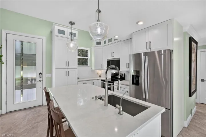 Kitchen featuring white shakercabinetry, stainless steel appliances, a center island with sink, and recessed lighting