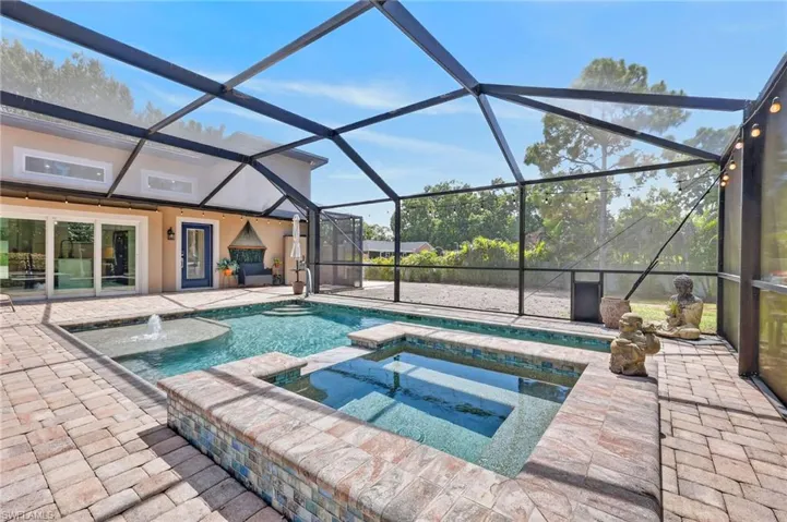 Screened enclosure featuring a swimming pool, integrated spa, and paver patio