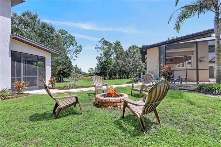 Manicured lawn with a brick fire pit, screened patio, and mature landscaping