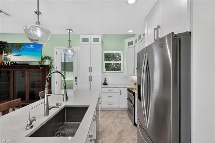 Kitchen featuring white cabinetry, stainless steel appliances, a large island with an undermount sink, and recessed lighting