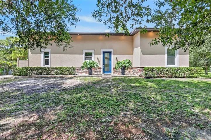Stucco exterior with stone accent detailing, a vibrant blue entry door, and recessed soffit lighting