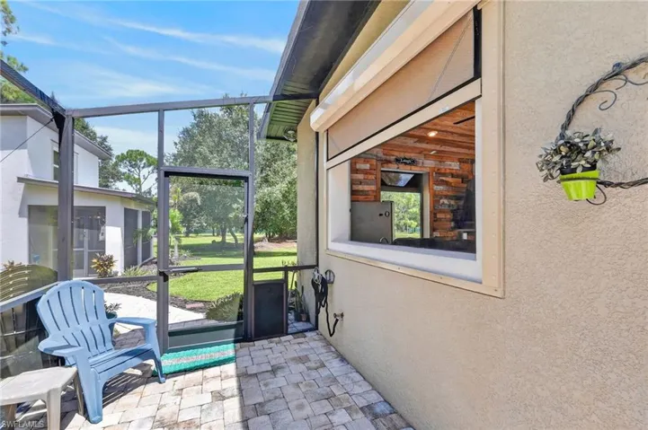 Screened patio with paver flooring, exterior window with roll-down shade, and stucco exterior finish