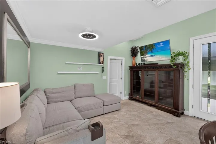 Tiled flooring with crown molding, a built-in display cabinet, and a door with frosted glass panels