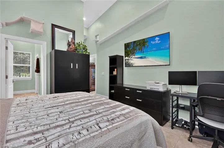 Vaulted ceiling with high-mounted ledges, light green painted walls, and neutral tile flooring