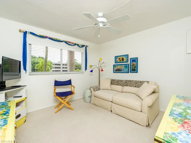 Living area with light colored carpet and a ceiling fan