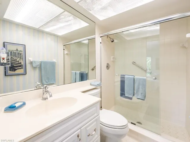 Full bathroom with vanity, wallpapered walls, and a stall shower