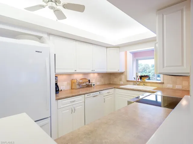 Kitchen with white appliances, light countertops, and white cabinetry