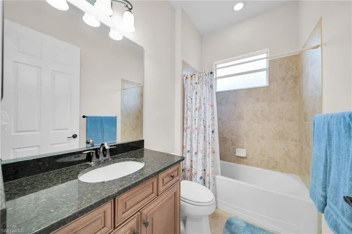 Bathroom featuring vanity, shower / bath combo, and light tile patterned floors