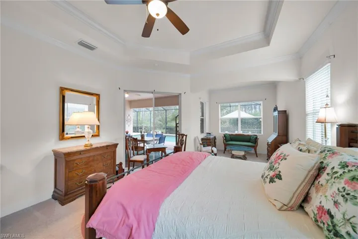 Bedroom with carpet, a ceiling fan, a sunroom, a raised ceiling, and crown molding