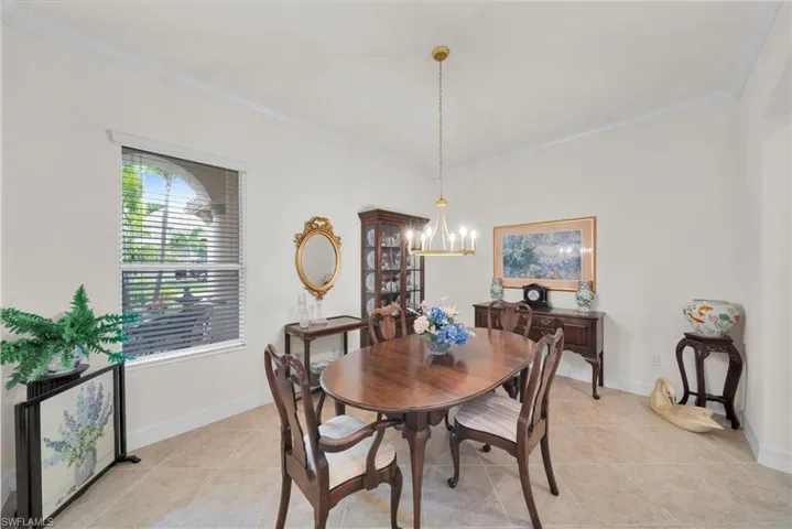 Dining room with crown molding, light tile patterned floors, and a chandelier