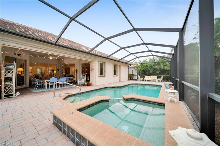 View of swimming pool with a sunroom, a patio area, glass enclosure, and a pool with connected hot tub