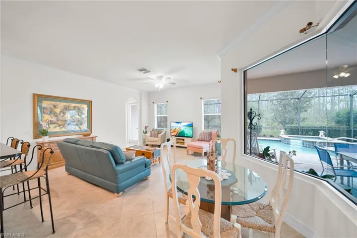 Dining area featuring a ceiling fan, ornamental molding, light tile patterned flooring, and a sunroom
