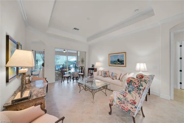 Living area featuring arched walkways, tile patterned floors, a raised ceiling, and crown molding