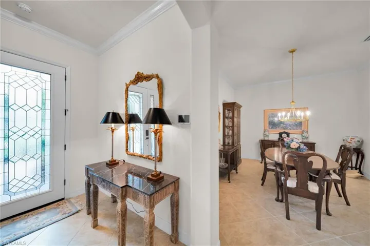 Foyer with crown molding, light tile patterned floors, and a chandelier