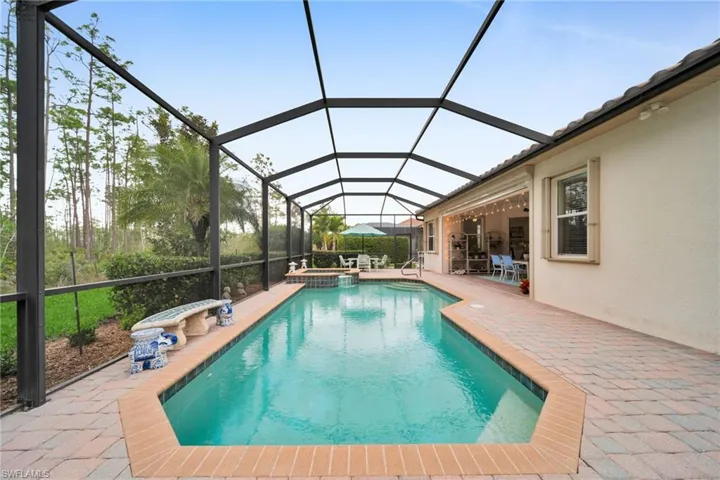 View of pool with a sunroom, a lanai, a pool with connected hot tub, and a patio area