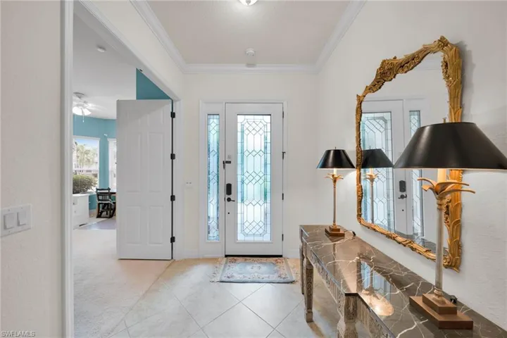 Foyer entrance featuring ornamental molding, light tile patterned floors, and light carpet