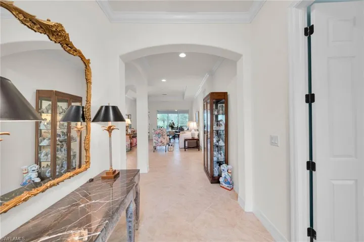 Hall with arched walkways, light tile patterned floors, recessed lighting, and crown molding