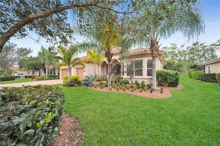 View of front of home with a front lawn, a tiled roof, stucco siding, and driveway