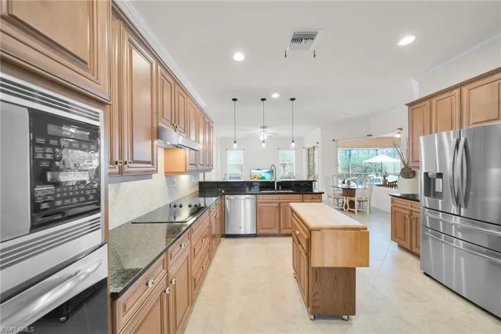 Kitchen with stainless steel appliances, hanging light fixtures, recessed lighting, a peninsula, and dark stone countertops