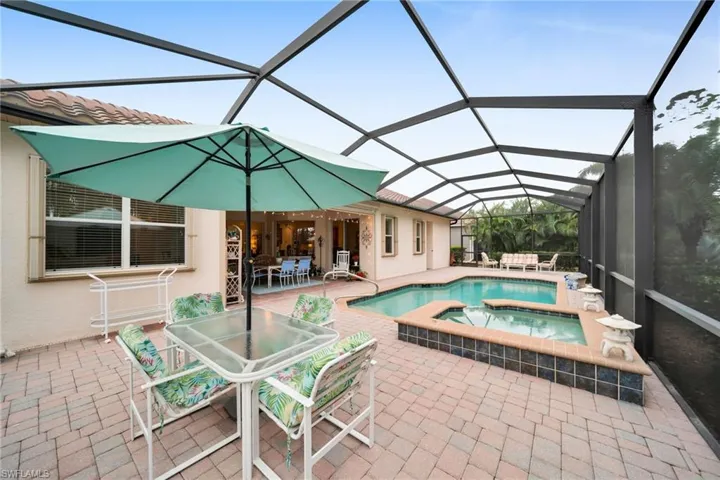 View of pool with a sunroom, outdoor dining space, a patio, a lanai, and a pool with connected hot tub