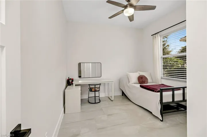 Tiled bedroom featuring ceiling fan
