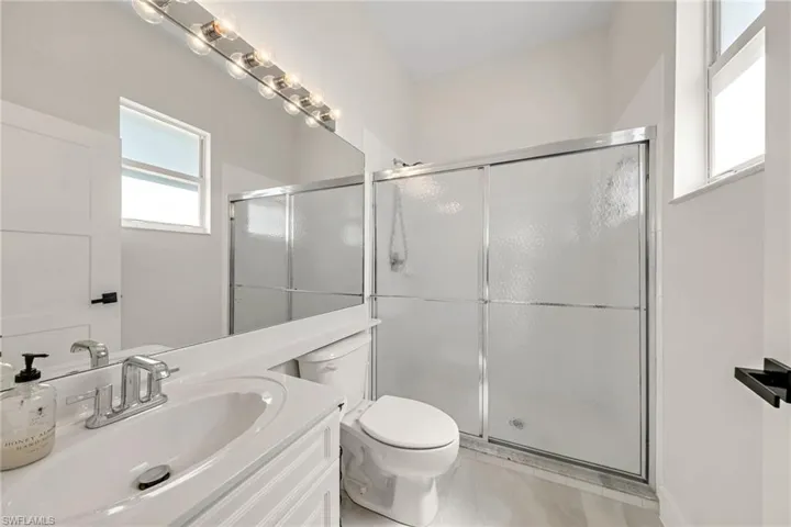 Bathroom with walk in shower, tile patterned floors, vanity, and toilet