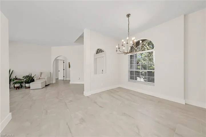 Tiled empty room featuring a notable chandelier
