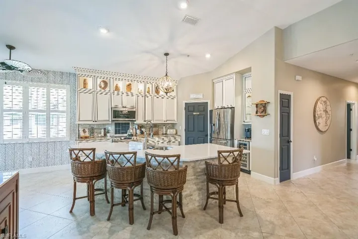 Kitchen featuring an island with sink, lofted ceiling, decorative light fixtures, appliances with stainless steel finishes, and a breakfast bar area