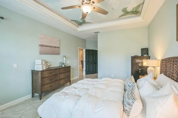 Tiled bedroom featuring ceiling fan and a raised ceiling