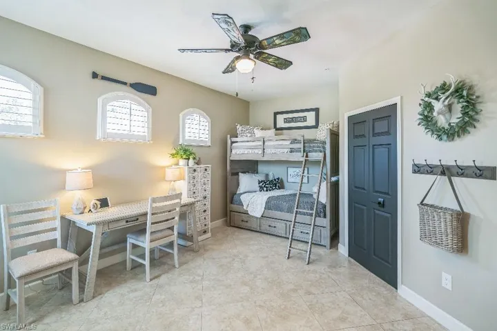 Tiled bedroom with ceiling fan and multiple windows