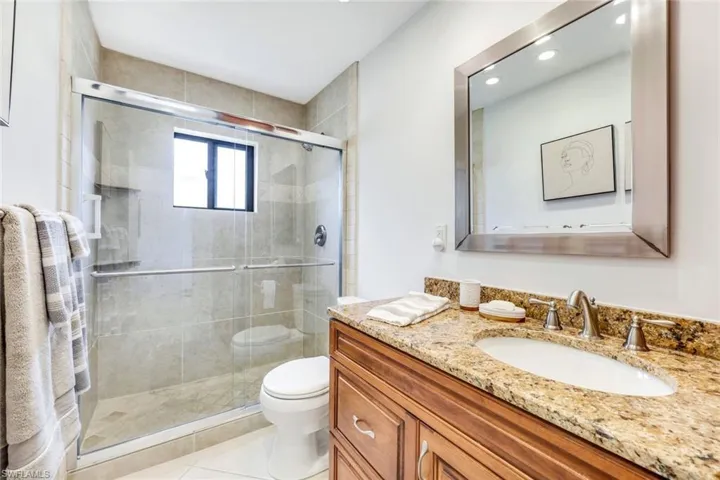 Bathroom featuring vanity, toilet, tile patterned floors, and walk in shower