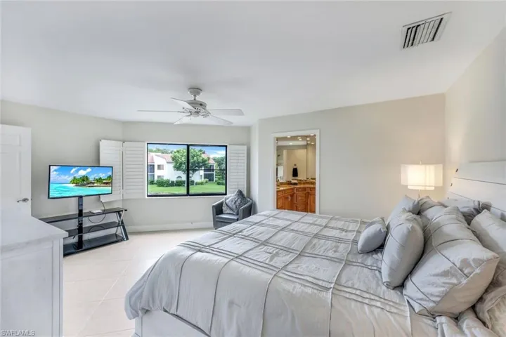 Bedroom featuring ensuite bath, ceiling fan, and light tile patterned floors