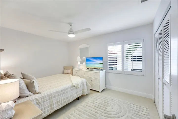 Bedroom with a closet, light tile patterned floors, and ceiling fan
