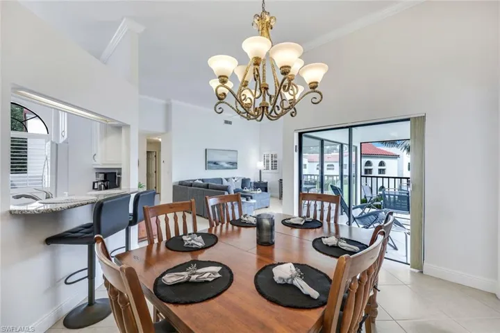 Tiled dining area featuring a chandelier and crown molding