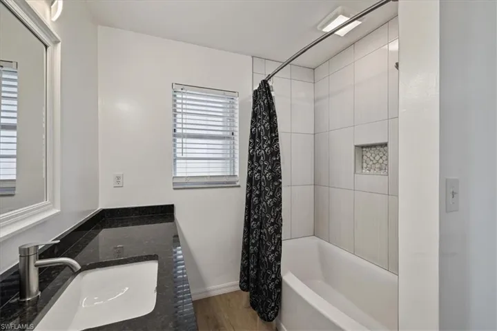 Bathroom featuring shower / bathtub combination with curtain, vanity, and light wood-style floors